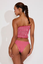Woman wearing a red and white checkered bikini against a white background