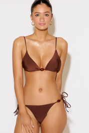 Woman wearing a brown bikini against a white background