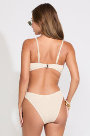 Model is wearing a peach seashell detail smocked strapless bikini set on a white background.