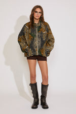 Person wearing a camouflage jacket and black boots on a white background