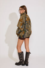 Person wearing a camouflage jacket and black boots on a white background