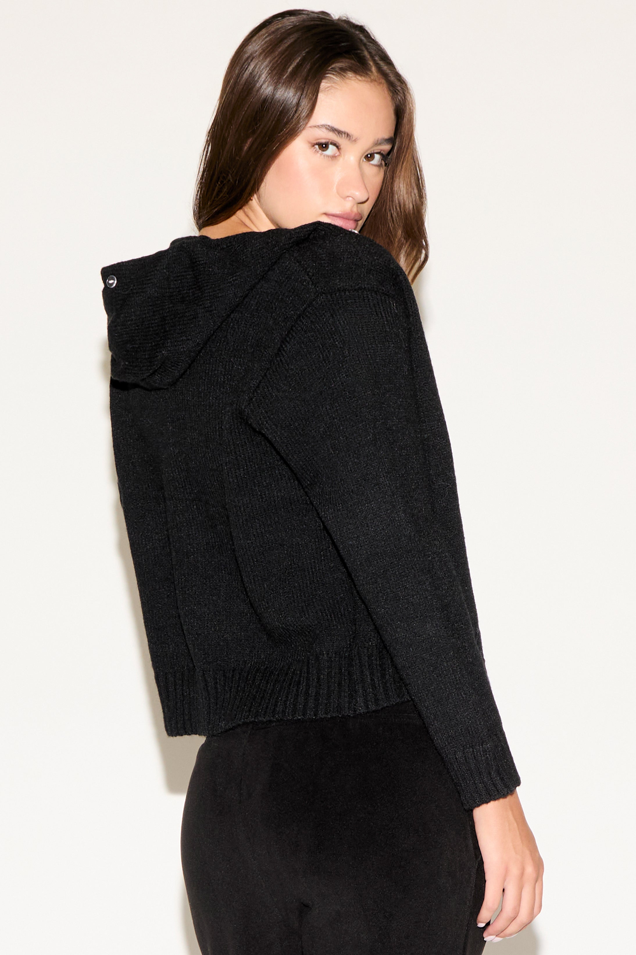 Woman wearing a black hooded sweater against a white background