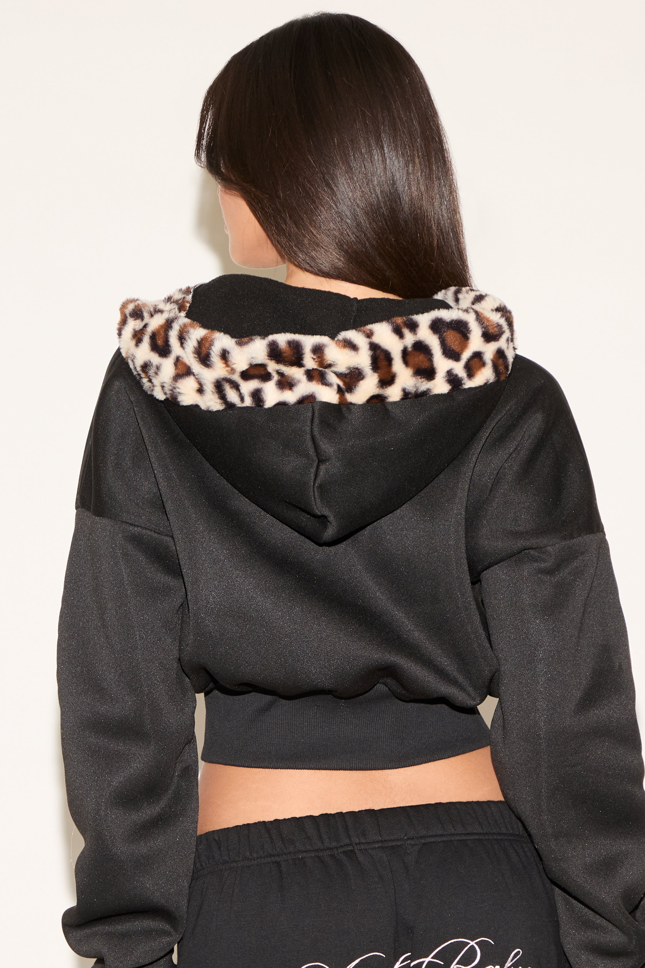 Black hoodie with leopard print trim worn by a person on a plain background