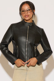 Woman wearing a black leather jacket and denim skirt on a white background