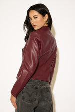 Woman wearing a burgundy leather jacket against a white background