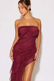 Woman wearing a burgundy strapless dress against a white background
