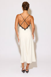 Woman wearing a white dress with black lace details on a plain background