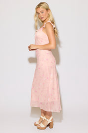 Model is wearing a pink ruffle strap v neck floral column maxi dress on a white background. 