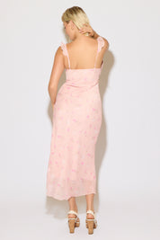 Model is wearing a pink ruffle strap v neck floral column maxi dress on a white background. 