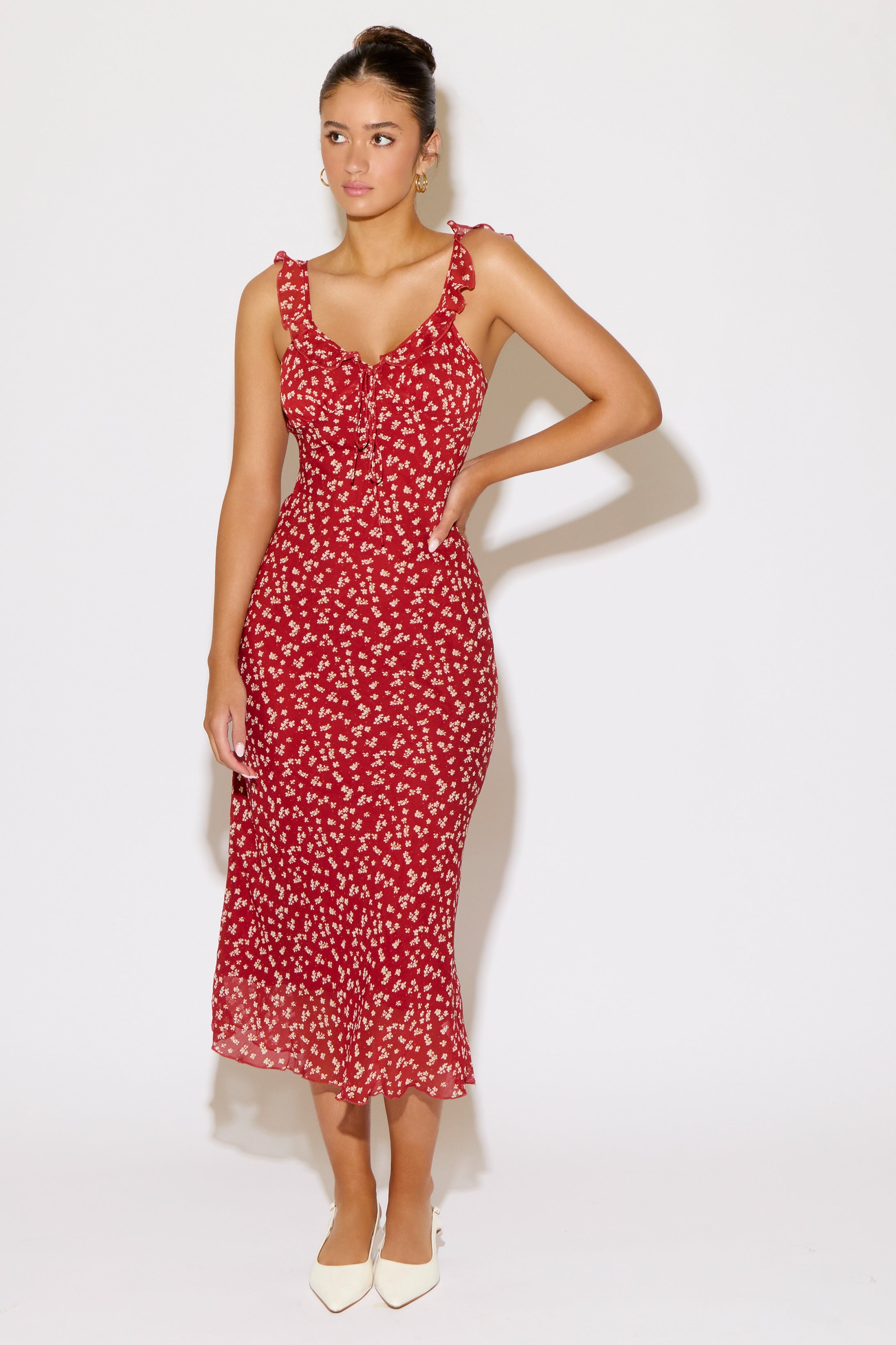 Woman wearing a red ditsy floral dress on a white background