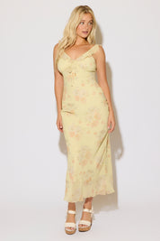 Model is wearing a yellow floral print tie bust strap maxi dress on a white background. 