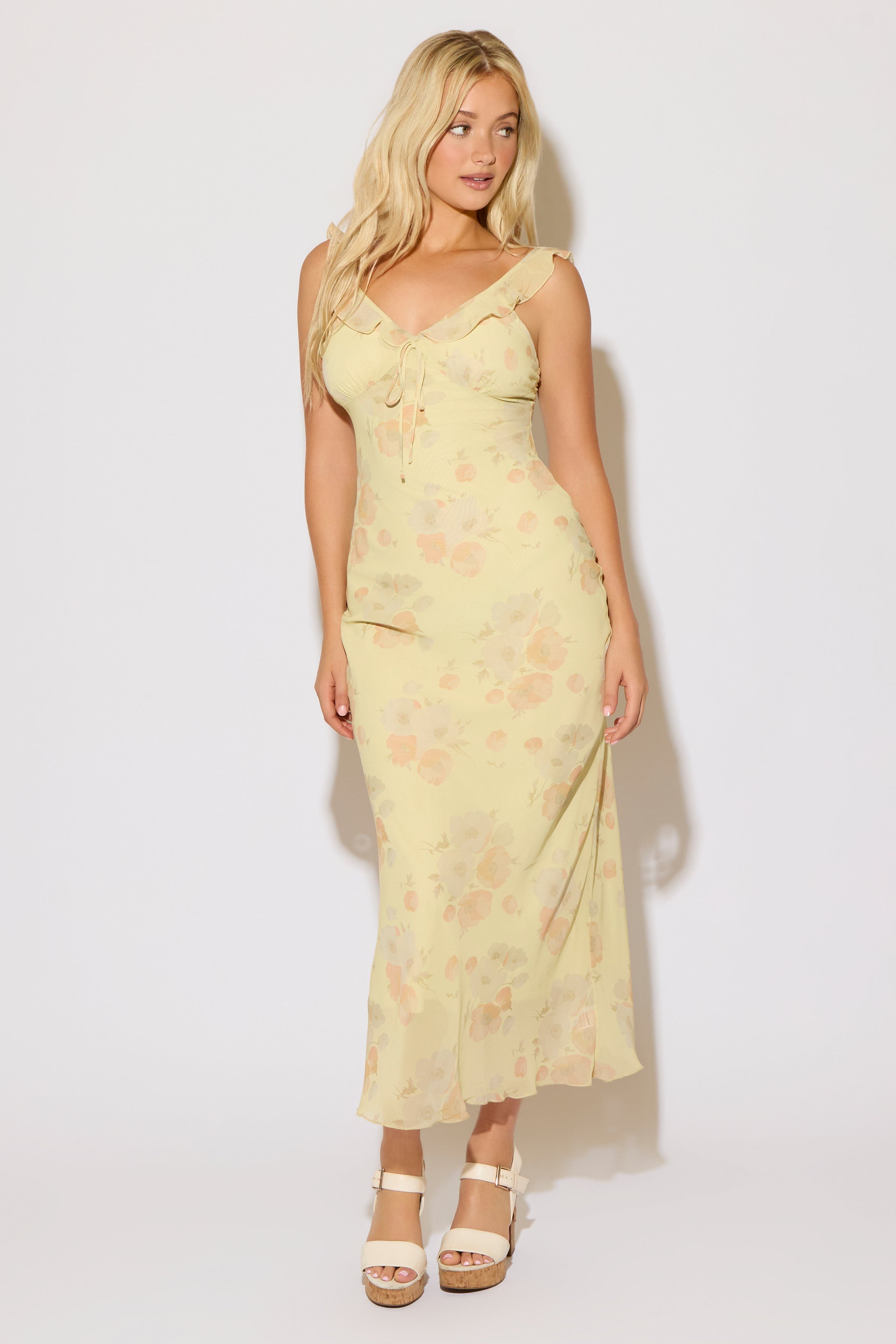 Model is wearing a yellow floral print tie bust strap maxi dress on a white background. 
