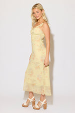 Model is wearing a yellow floral print tie bust strap maxi dress on a white background. 