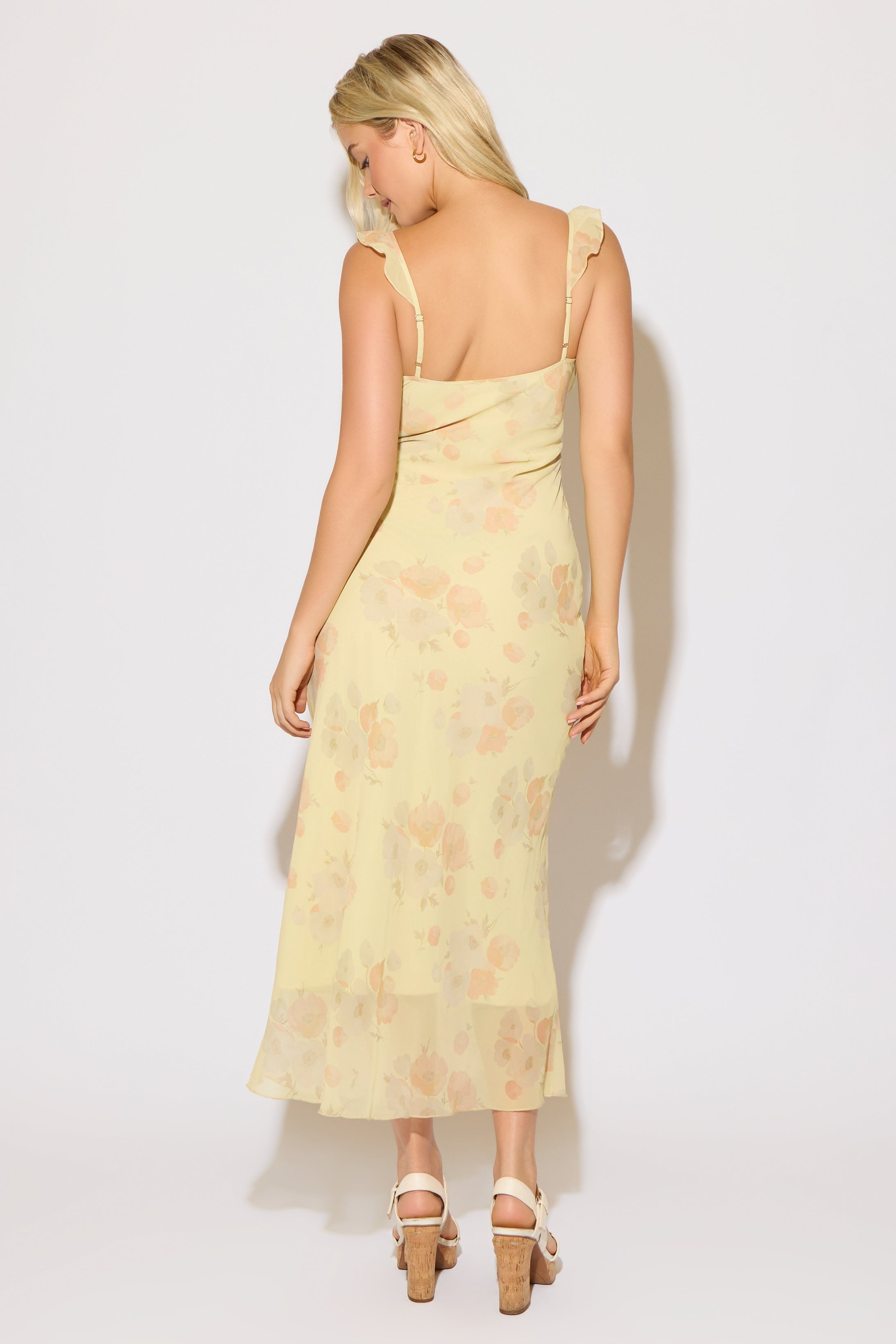 Model is wearing a yellow floral print tie bust strap maxi dress on a white background. 