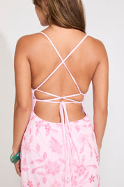 Model is wearing a pink sequin flower and vine design tie neck mini dress on a white background.