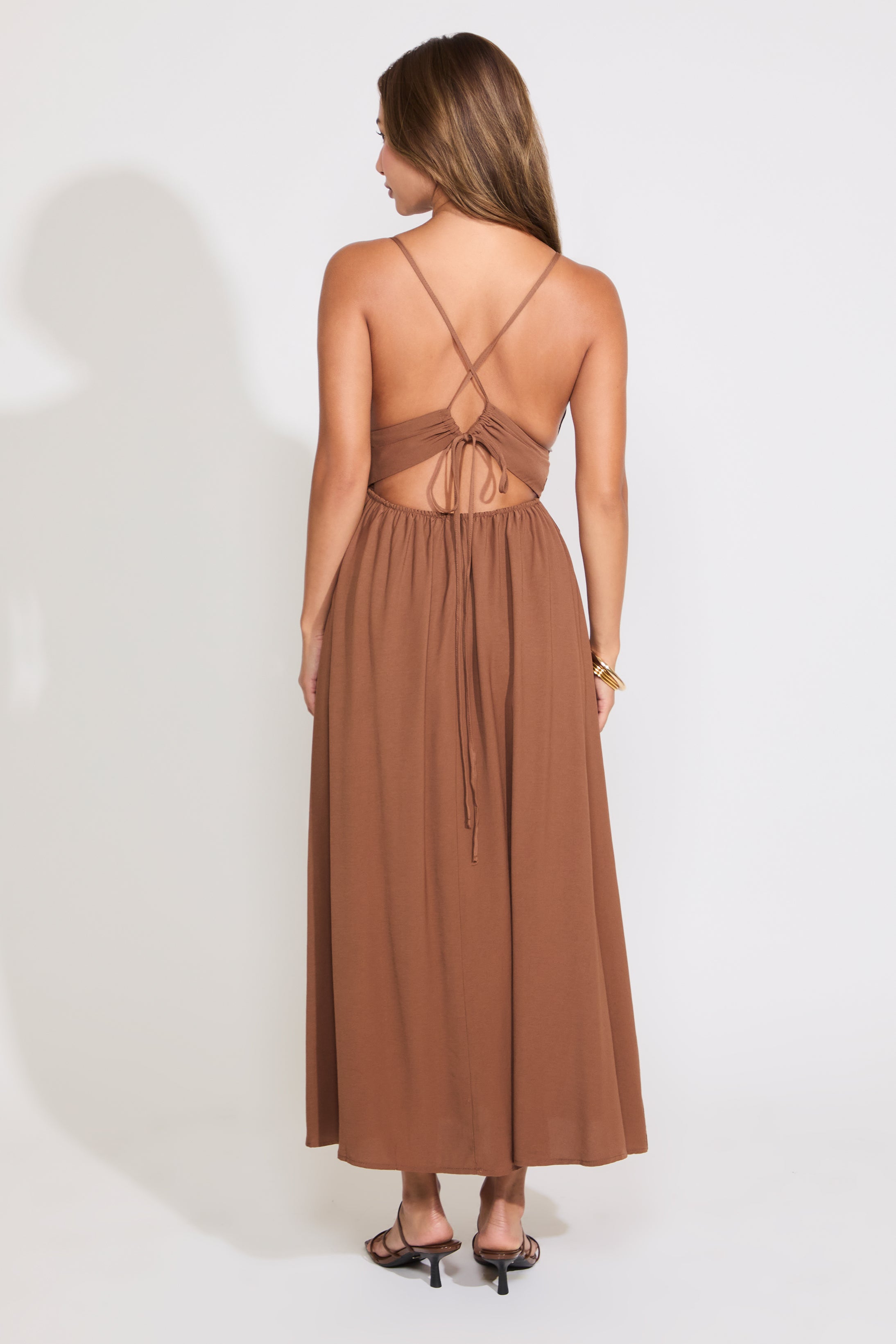 Model is wearing a brown sleeveless maxi dress on a white background.