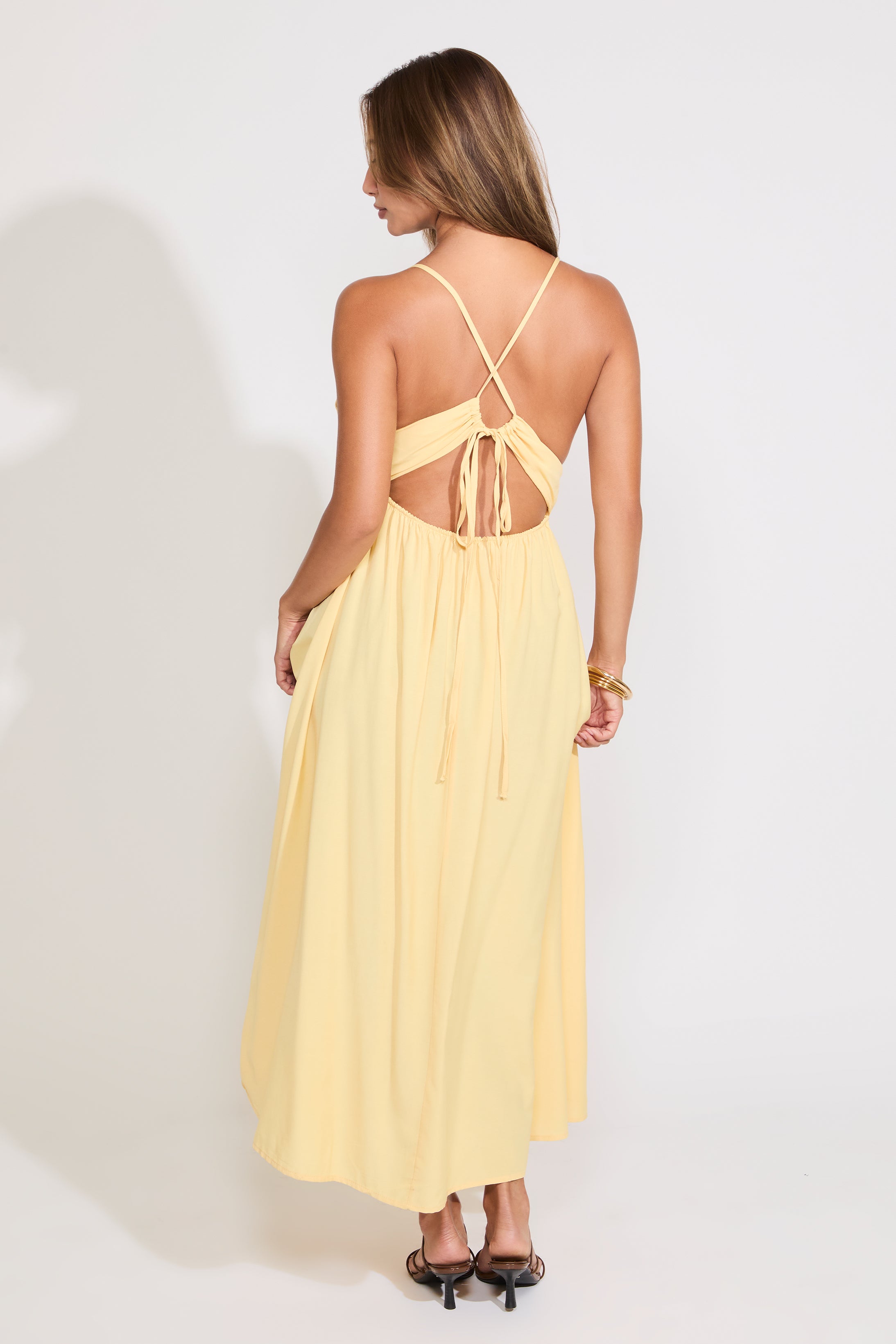 Model is wearing a yellow sleeveless maxi dress on a white background.