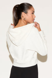 Back of model wearing a gray zip jacket with a relaxed fit an a black mini skirt , standing against a neutral studio background.