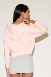 Back of model wearing a pink zip jacket with a relaxed fit an a gray mini skirt , standing against a neutral studio background.