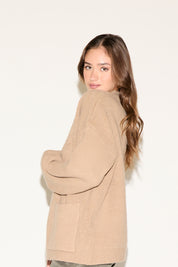 Woman wearing a beige cardigan against a white background