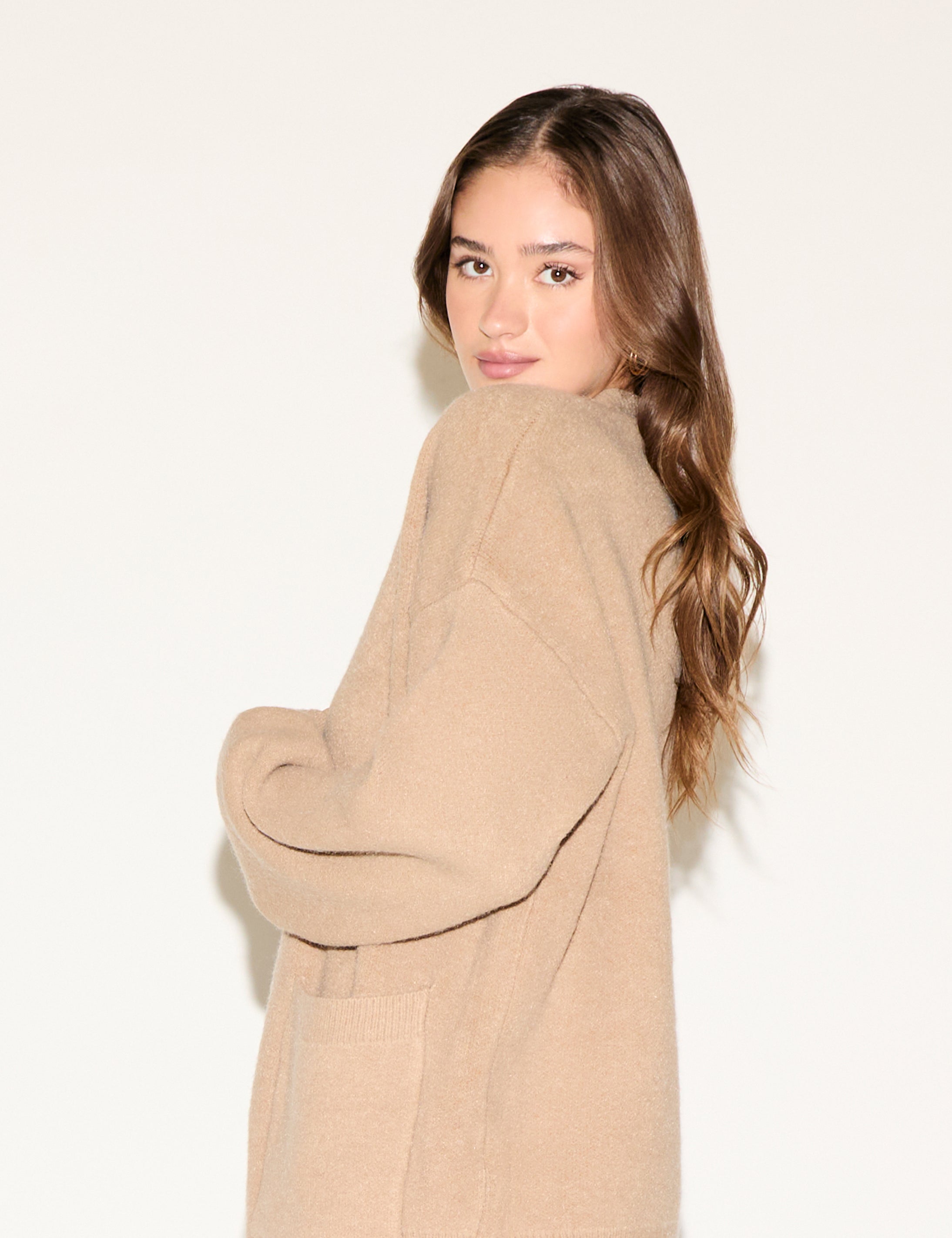 Woman wearing a beige cardigan against a white background