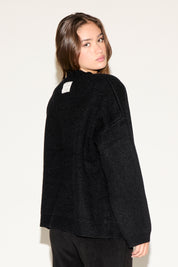 Woman wearing a black sweater against a white background