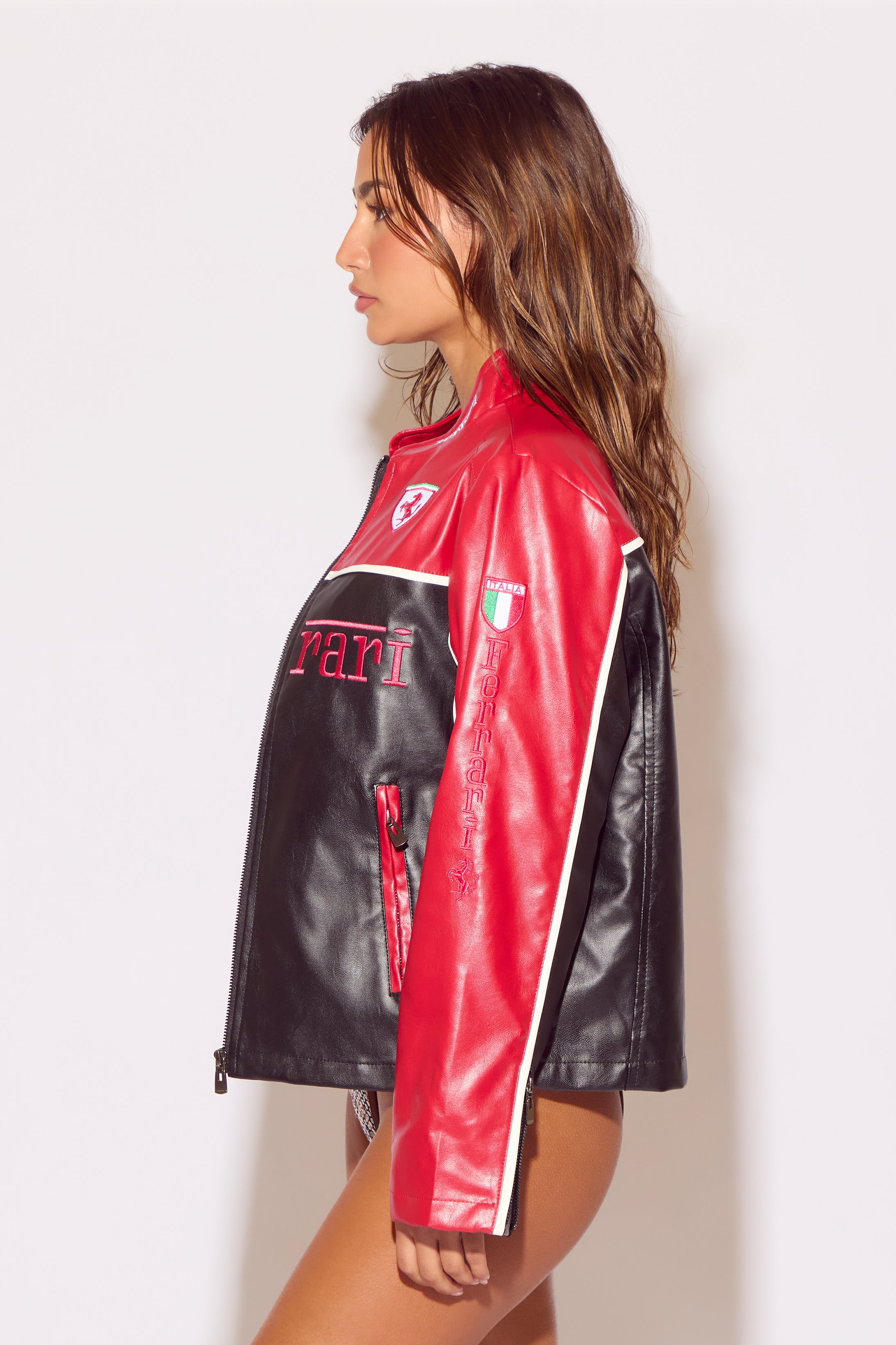 Woman wearing a red and black Ferrari leather jacket against a white background