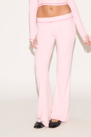 Person wearing a pink outfit with matching pants on a white background