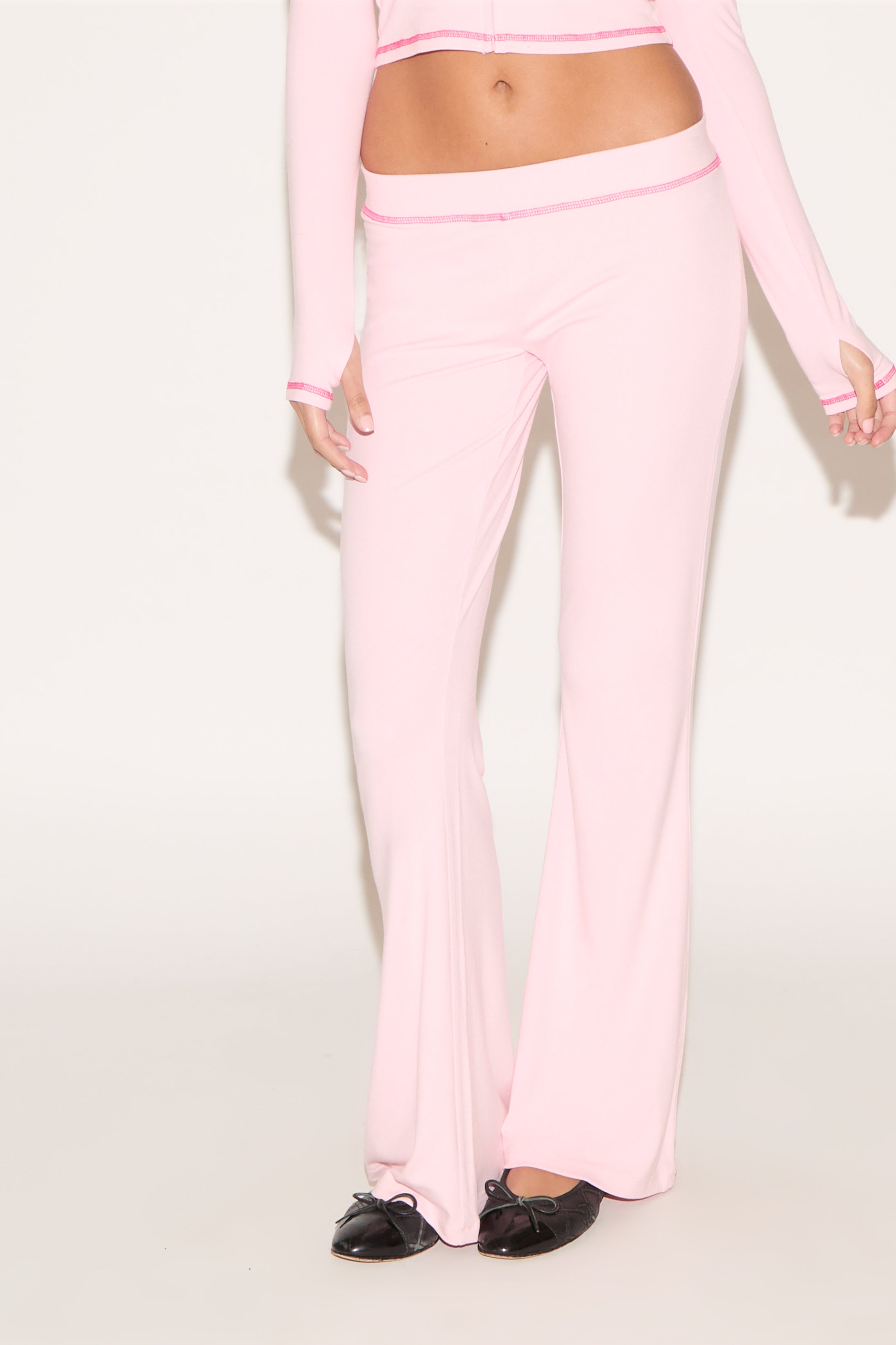 Person wearing a pink outfit with matching pants on a white background