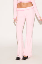 Person wearing a pink outfit with matching pants on a white background