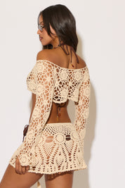 Woman wearing a beige crochet cover-up against a white background
