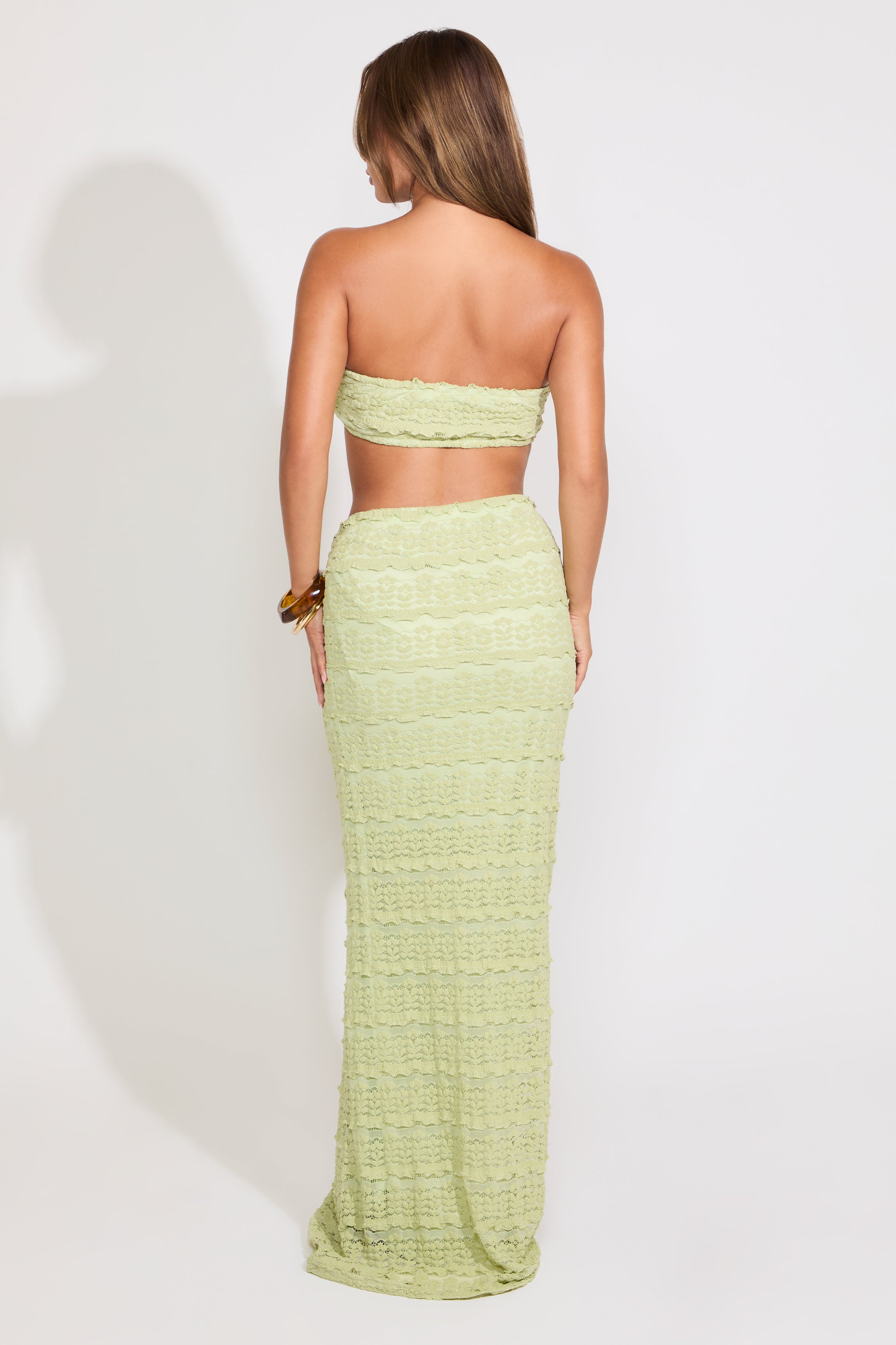 Model is wearing a green textured shell detail bralette top and maxi skirt set on a white background.