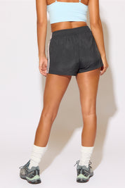 Person wearing black shorts with a white stripe on a plain background