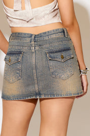 Denim skirt worn by a person on a plain background