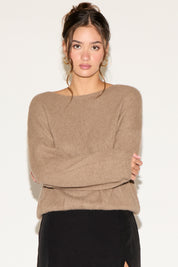 Woman wearing a beige sweater against a white background