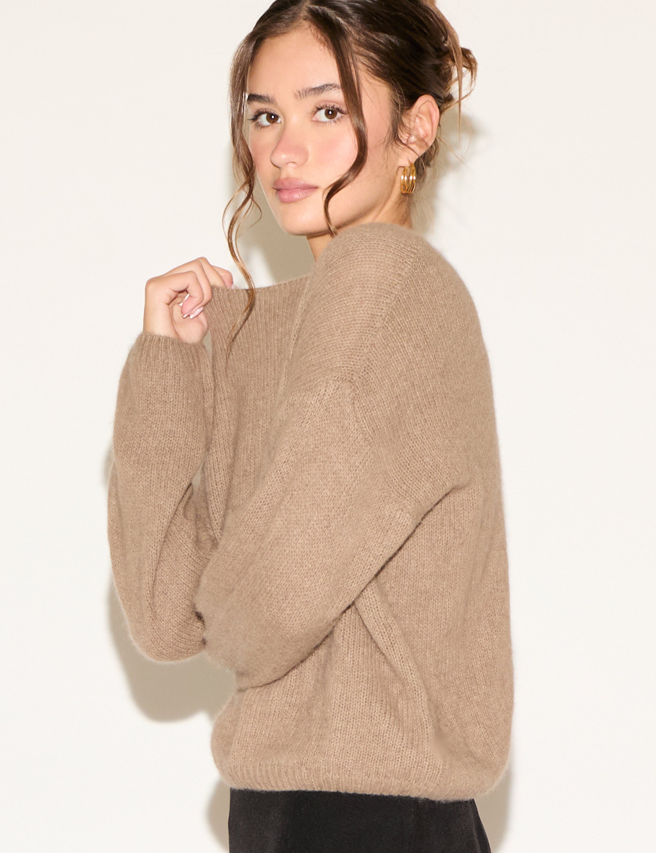 Woman wearing a beige sweater against a plain background