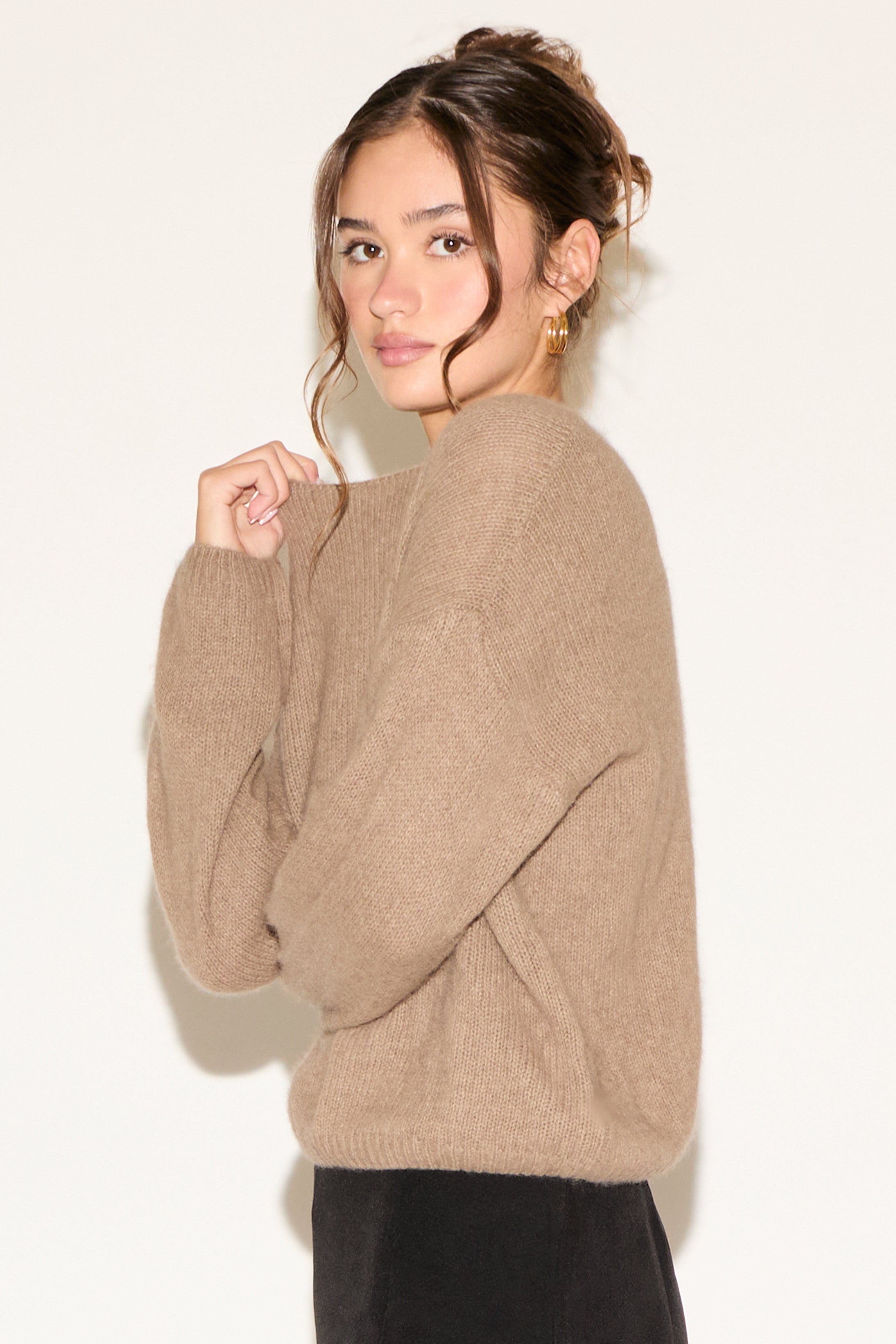 Woman wearing a beige sweater against a plain background