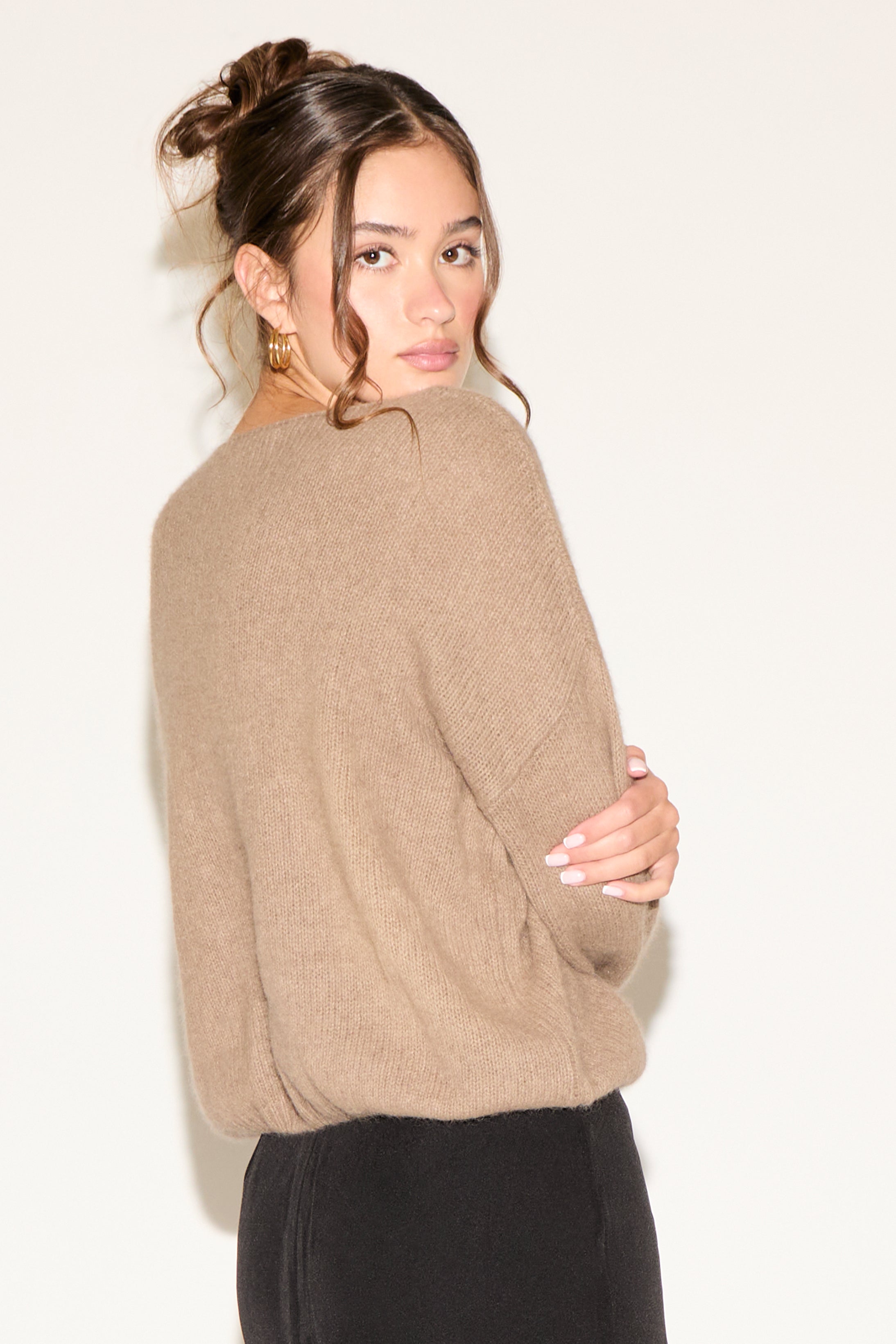 Woman wearing a beige sweater against a white background