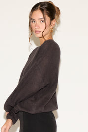 Woman wearing a dark gray sweater against a white background