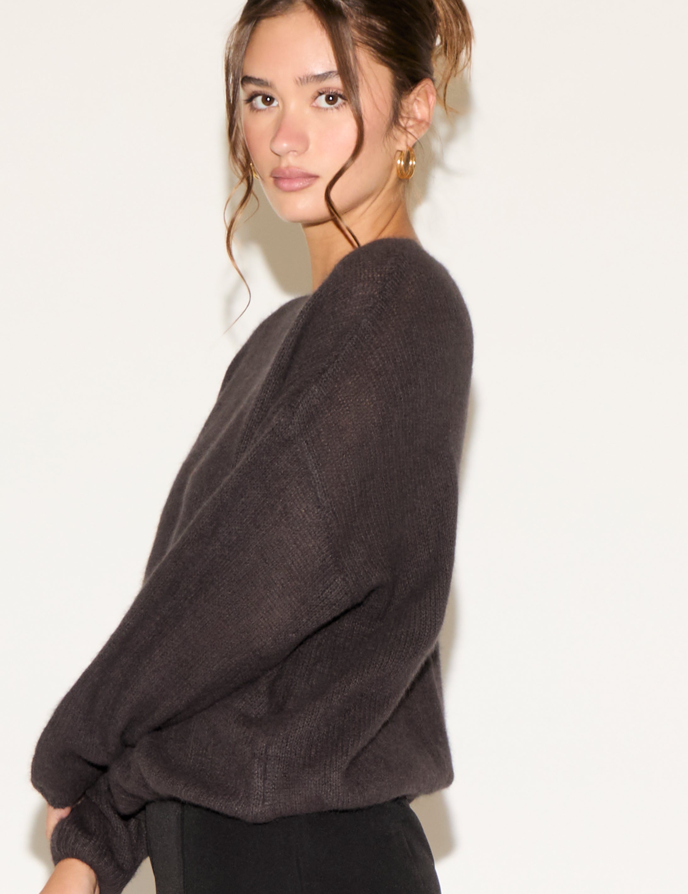 Woman wearing a dark gray sweater against a white background