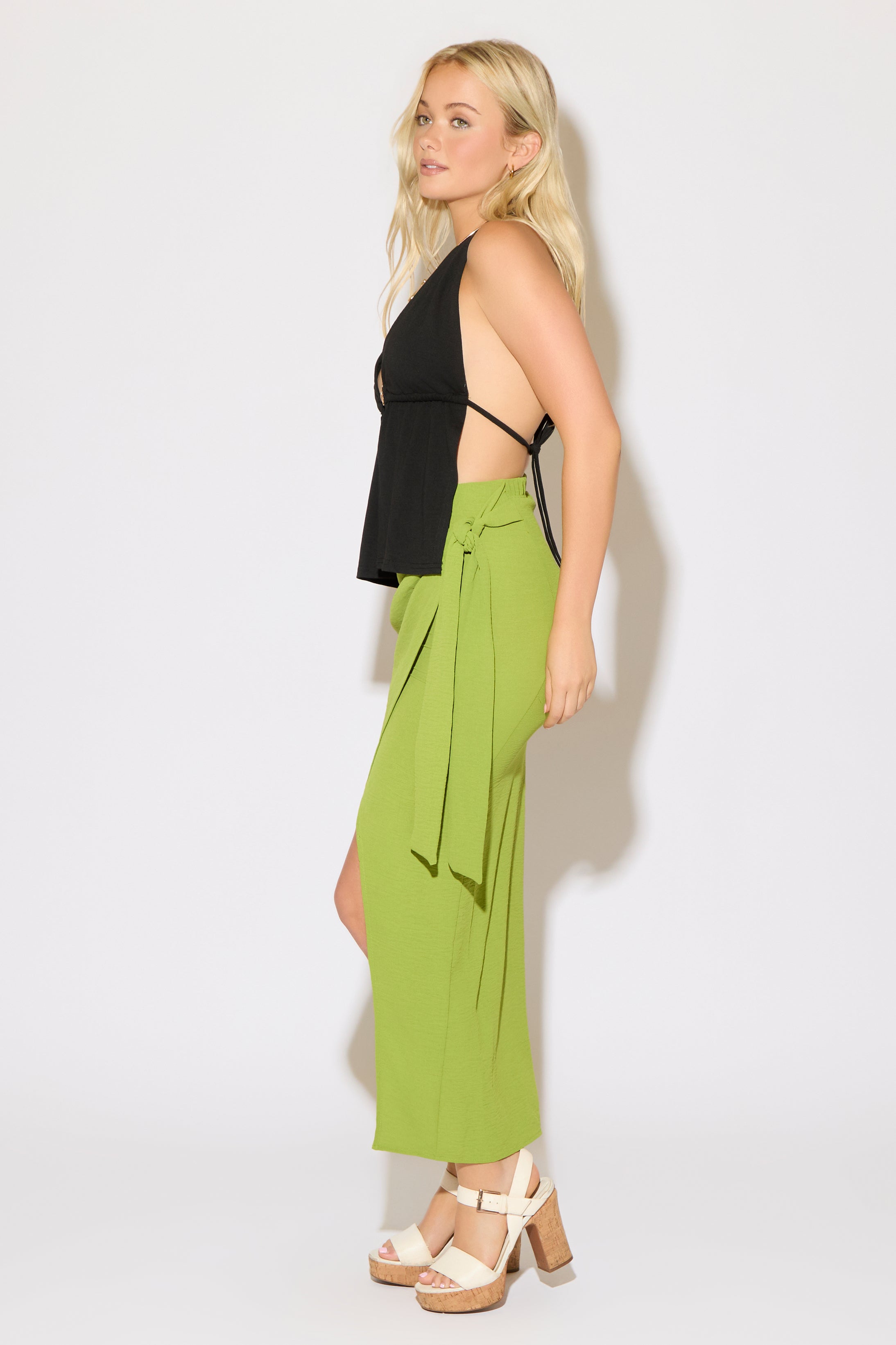 Model is wearing a black bead detail tie neck and back butterfly top with a green maxi skirt on a white background.