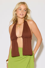 Model is wearing a brown bead detail tie neck and back butterfly top with a green maxi skirt on a white background.