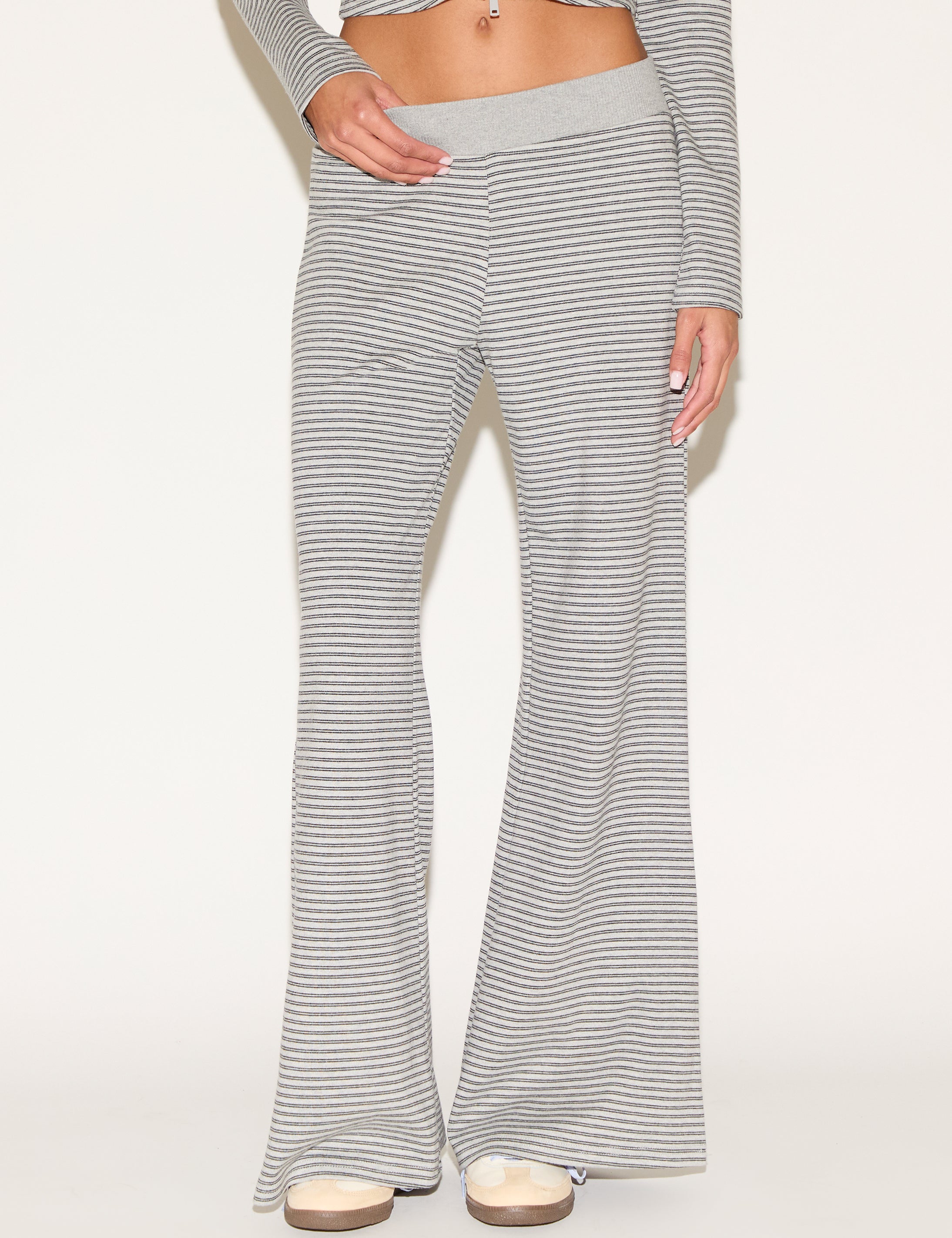 Close-up of matching gray-and-white striped lounge pants with a soft elastic waistband and relaxed wide-leg fit, styled with platform sandals against a clean, neutral background.