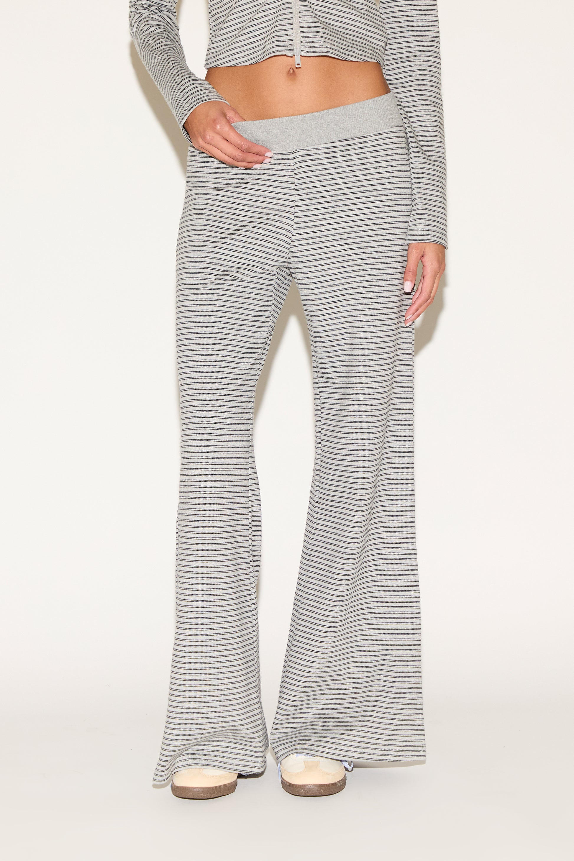 Close-up of matching gray-and-white striped lounge pants with a soft elastic waistband and relaxed wide-leg fit, styled with platform sandals against a clean, neutral background.