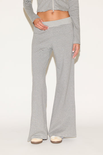 Close-up of matching gray-and-white striped lounge pants with a soft elastic waistband and relaxed wide-leg fit, styled with platform sandals against a clean, neutral background.