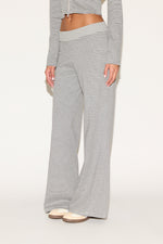 Close-up of matching gray-and-white striped lounge pants with a soft elastic waistband and relaxed wide-leg fit, styled with platform sandals against a clean, neutral background.