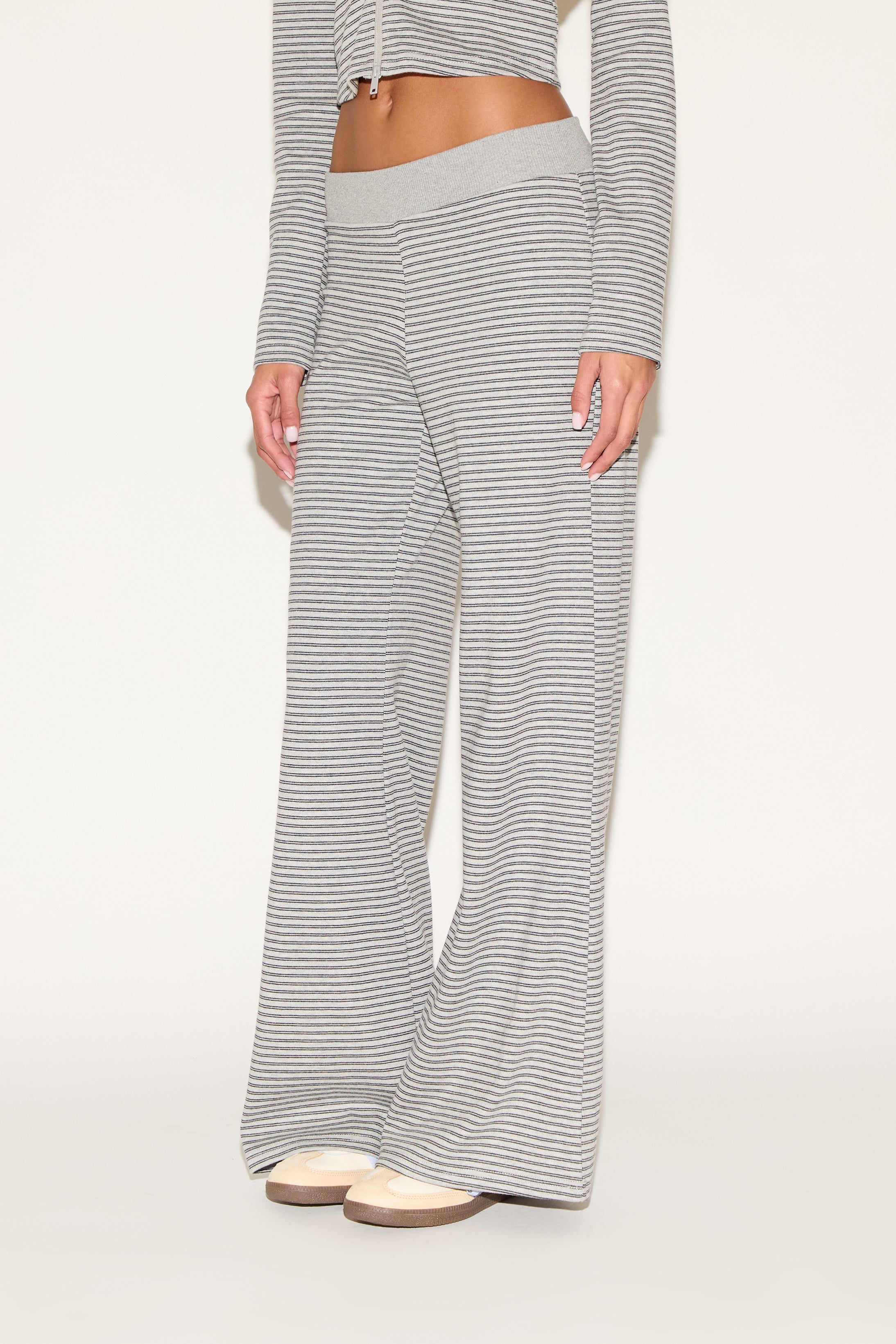 Close-up of matching gray-and-white striped lounge pants with a soft elastic waistband and relaxed wide-leg fit, styled with platform sandals against a clean, neutral background.