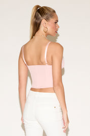 Woman in a pink corset and white pants.