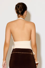 Woman wearing a halter top and skirt against a plain background