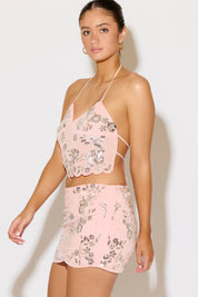 Woman wearing a pink floral two-piece set against a white background